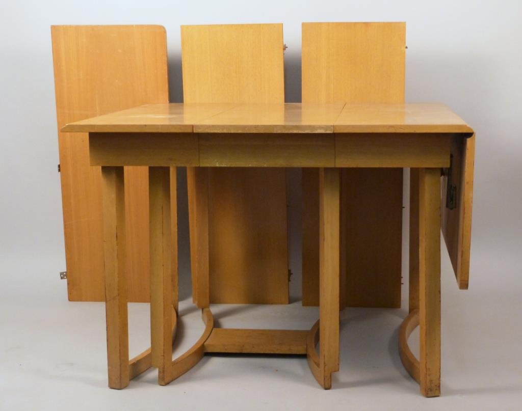 John Stuart Drop Leaf and Extension Table: Blonde wood, sculpted base, collapsed: 42 W x 40" D x 29" H, drop leaves: 16" W, leaves: 14" W, one drop leaf detached, some veneer losses and other wear."