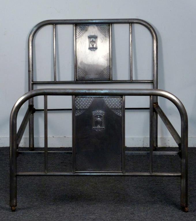 Art Deco Tubular Metal Bed: Tubular construction, panel with repousse urn and perforation suspended within head and foot board rails, 47" W x 81" D x 49" H, on casters, one caster bent.