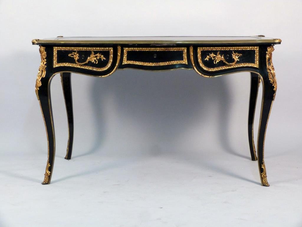 French Ebonized Bureau Plat: Ebonized carved wood frame, tooled leather surface, gilt metal mounted edges and ornaments. Oak drawer interiors. 53" W X 33" D X 31 1/2" H.