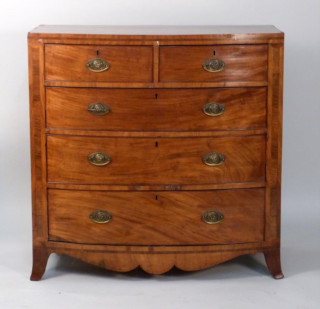 Antique English Bow Front Chest: Banded front, 5 drawers, brass lion face pulls and escutcheons. 42" W X 21" D 41 1/2 H. Some losses to veneer, damage to back leg.