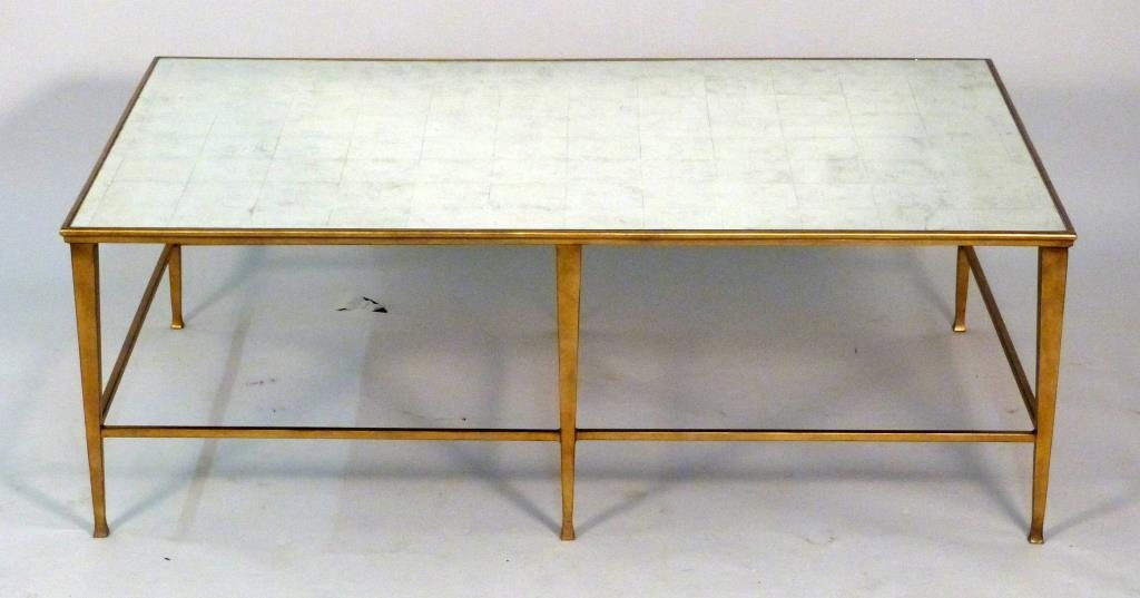 Hollywood Regency Style Cocktail Table: Faux silver leaf mirrored top, brass toned frame with outer structures. 50" W X 31" D X 17" H.