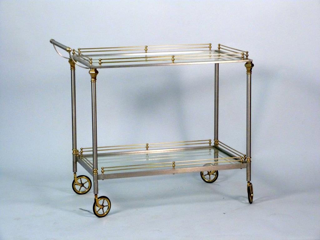Hollywood Regency Style Mixed Metal Bar Cart: Italian, steel frame with brass accents. 2 tiers( both with inset glass) with 4 spoked casters. Glass chipped. One wheel chipped.
