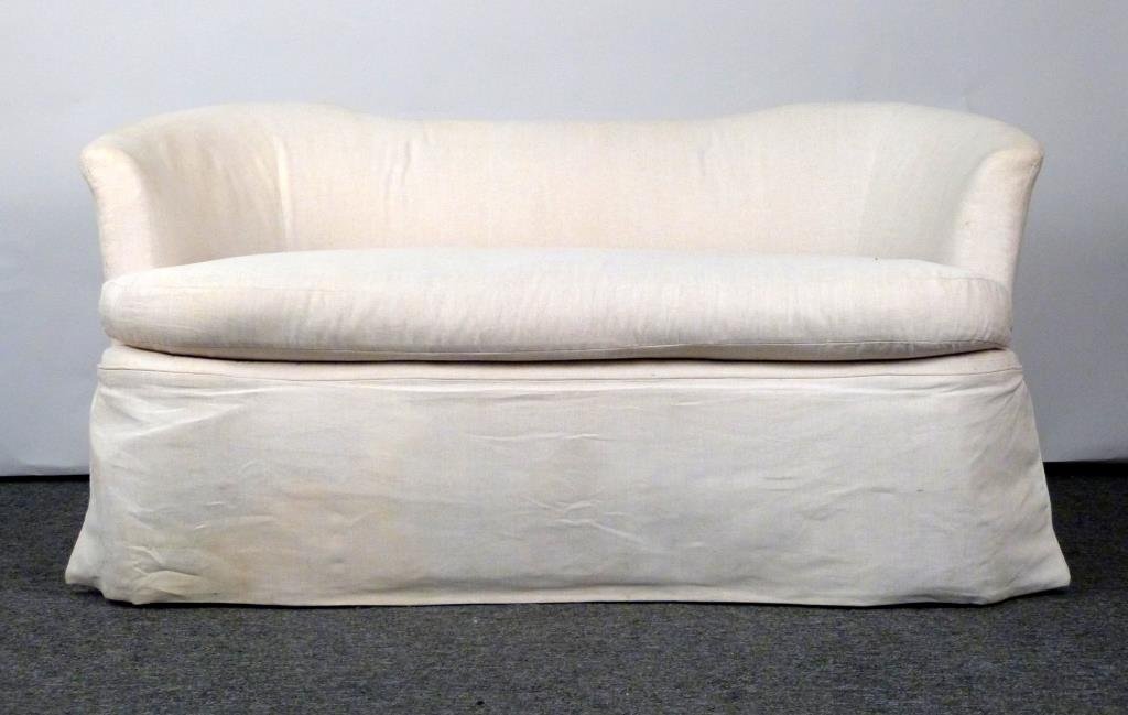 Contemporary Slip Covered Loveseat: Sculpted back and sides, on casters. 59" W X 30" D X 29 1/2" H. White upholstery in good condition. (Madison Avenue NYC Estate)