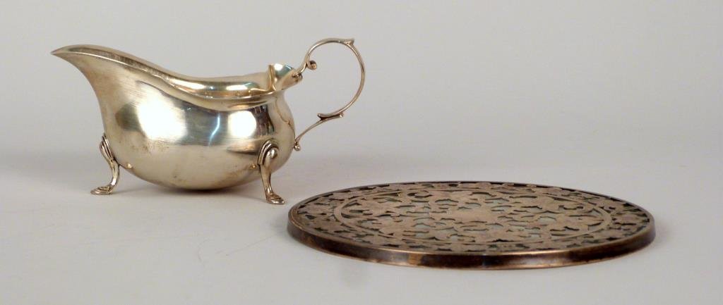 2 Sterling Silver Articles: J.E. Caldwell & Co. gravy boat (3.6 troy oz) and trivet with sterling overlay (glass as is). Boat: 2 12" H. (925 Park Ave Estate)