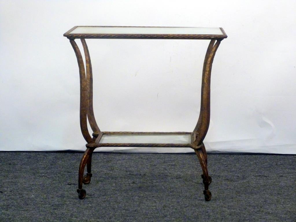 Mid Century Gilt Iron 2 Tier Occasional Table: Rope edges, reverse tapered swaying supports, upper tier mirror, lower tier glass as is, on casters. 23" W X 16" D X 24 1/2" H.