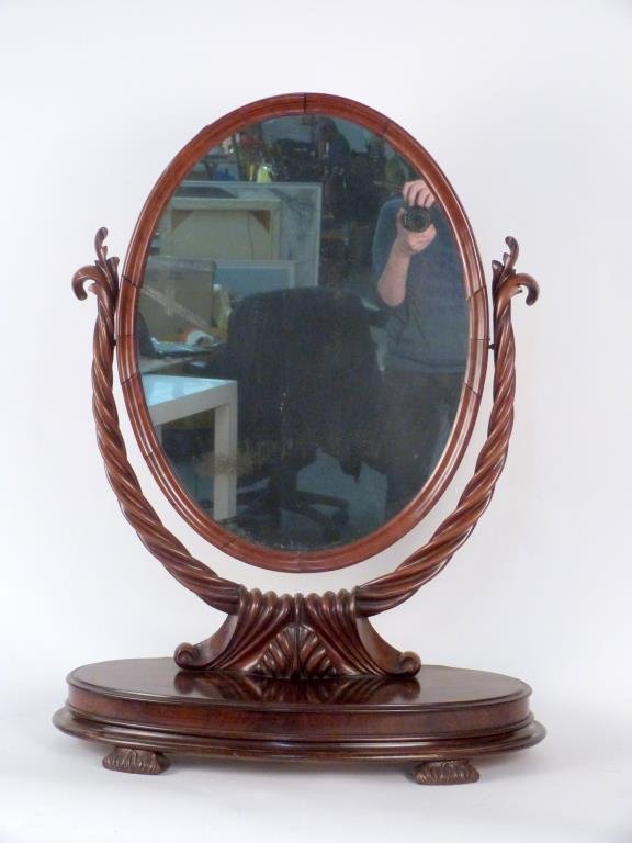 English Dressing Table Mirror: Foliate carved wood frame suspending oval pivoting mirror, on carved wood base. 29 W X 11" D X 37" H."