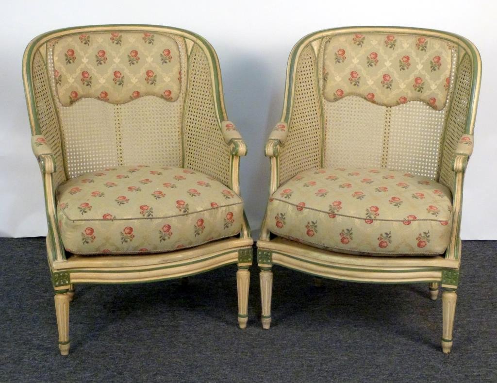 Pair of Louis XVI Style Bergeres: Painted carved wood frames, cane seats, backs, and arms, with upholstered cushion, headrest, and arm rests. 26" W X 28" D X 38" H. In good condition.