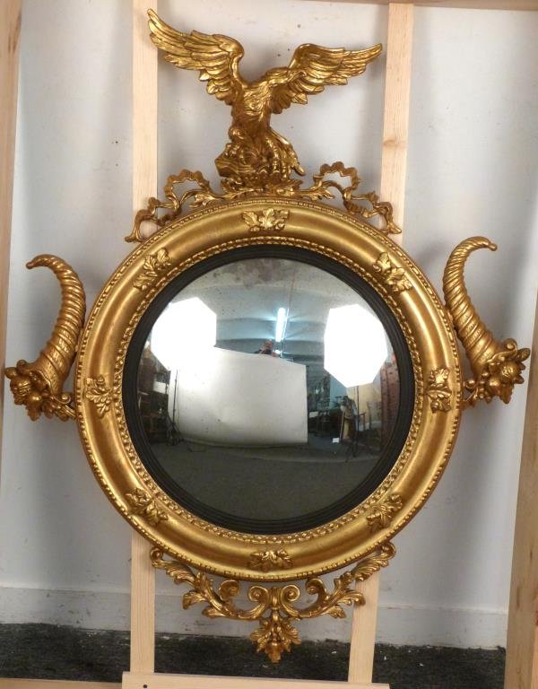 Federal Style Gilt Framed Convex Mirror: High spread winged American Eagle pediment over a convex "antiqued" glass with a reeded ebonized inner frame. Side mounted inverted cornucopias, all over a small bottom scroll drop. 54" X 44". Tempora