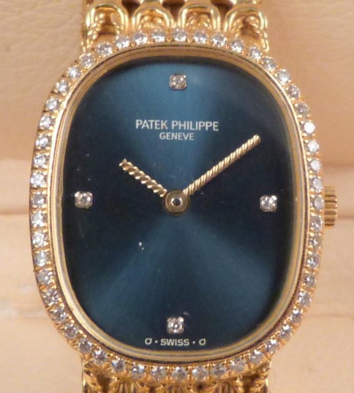 Ladies Patek Philippe Gold & Diamond Watch: Diamond surrounded bezel on dark blue face. Patek-Philippe Swiss band 750 (18K gold). Original Patek Philippe Box. (320 Central Park West Estate)