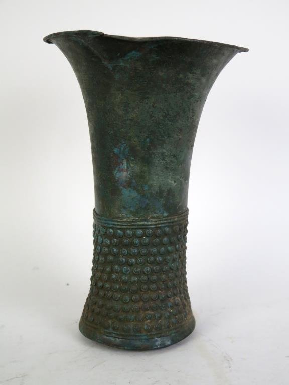 Pre-Columbian Style (?) Metal Beaker Vase: Waisted, with flared mouth, the lower portion with applied eyes flanked by applied bands, interior rattle (unseen). 9 H. Dented, separations at mouth."
