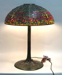 Tiffany Style Poinsettia Table Lamp: Leaded and stained glass shade signed Tiffany Studios NY (8.5 H X 22" W) on a bronze tree trunk form base also signed Tiffany Studios 561 (29" H X 14" dia). This is believed NOT to be by Tiffany. (Est