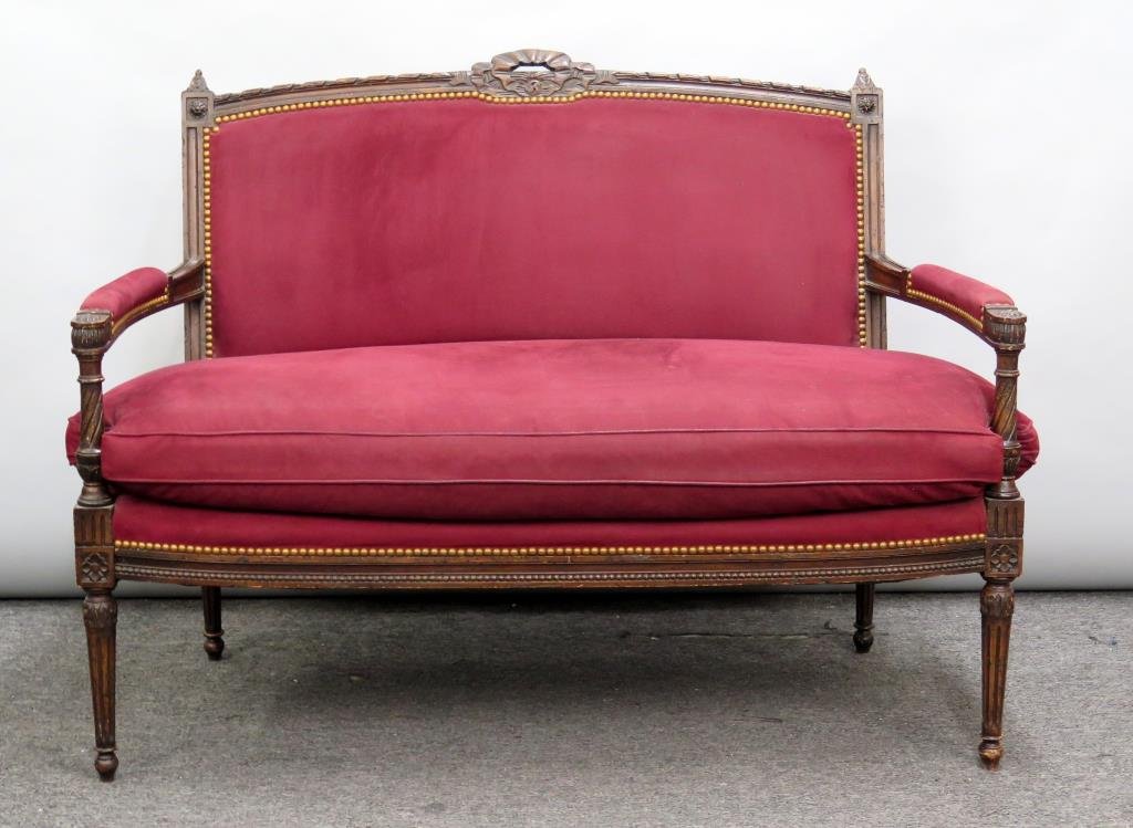 Louis XVI Style Open Arm Loveseat: Carved fruitwood with ribbon back and fluted, tapered legs. Fitted cushion. Studded and upholstered. Slightly worn. 50"W X 29"D X 38"H