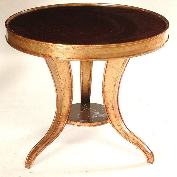 Gilded Round Center Table: TABLE. Gilded round center tables, the circular mahogany top with a gilt apron and three boldly curved legs centered by a lower shelf, from the Mark Hopkins Hotel, good condition, 30" w x 26 1/2" h.