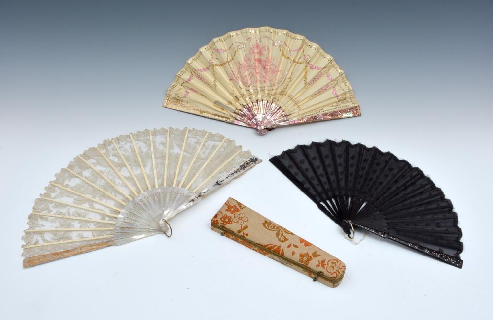Lot of three fans, decorated silk and lace: Lot of three fans including: one white silk with painted detail, images of cherubs, and shaped sequins, tinted, carved and inlaid mother of pearl rib, in fitted case; one white lace with carved and gi