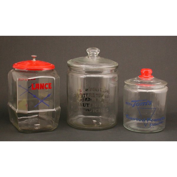 3 Glass Peanut Jars; 2 Toms & 1 Lance: JARS. Lot of three glass covered peanut jars; two by Tom's Peanuts, "Eat Tom's Peanut Butter Sandwiches" & "Enjoy Tom's roasted peanuts, delicious" and one by Lance, good condition, largest, 13 1/2" t