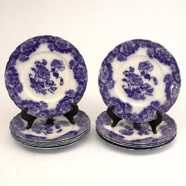 11 Matching Flow Blue Porcelain Luncheon Plates: PORCELAIN. Set of eleven matching flow blue porcelain luncheon plates, shaped floral edges with flowers and a note at the center, La Meride by New Wharf, good condition, 9" w.