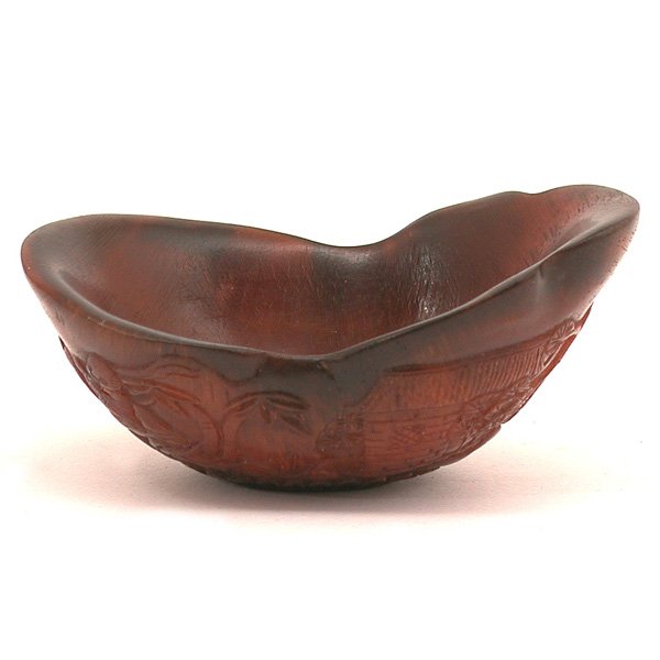 Chinese Carved Rhinoceros Libation Cup, Qing: CUP. Chinese carved Rhinoceros libation cup, the flared oval opening resting on a small flat base, the exterior carved with bamboo grove and pine tree with cranes in the sky and ruyi clouds, horn of g