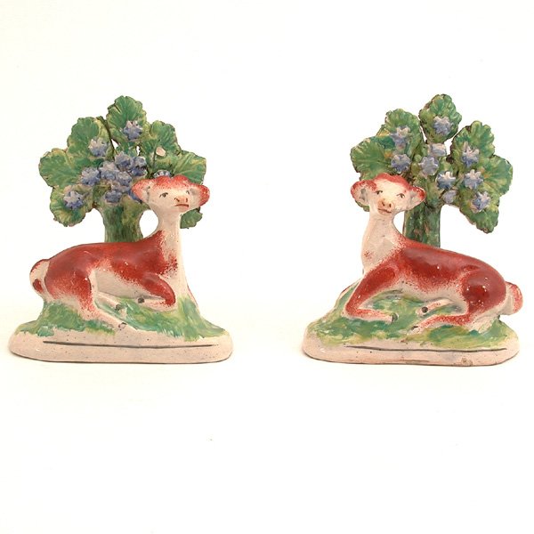 Pair of Staffordshire Walton-Type Cows: FIGURES. Staffordshire creamware Walton-type figural groups, first half of the 19th century, each polychrome decorated and modeled after a recumbent cow resting by a tree, on naturalistic base, 4 3/4"