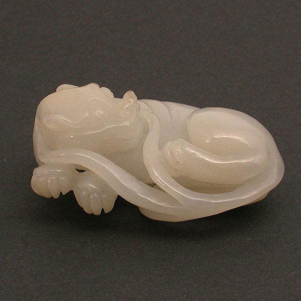 Chinese Carved White Jade Lion, 19th Century: CARVING. Chinese carved white jade lion, 19th Century. The beast shown in recumbent position with head turned back and tail coiled over the body, the semi-translucent stone in milky white color, light