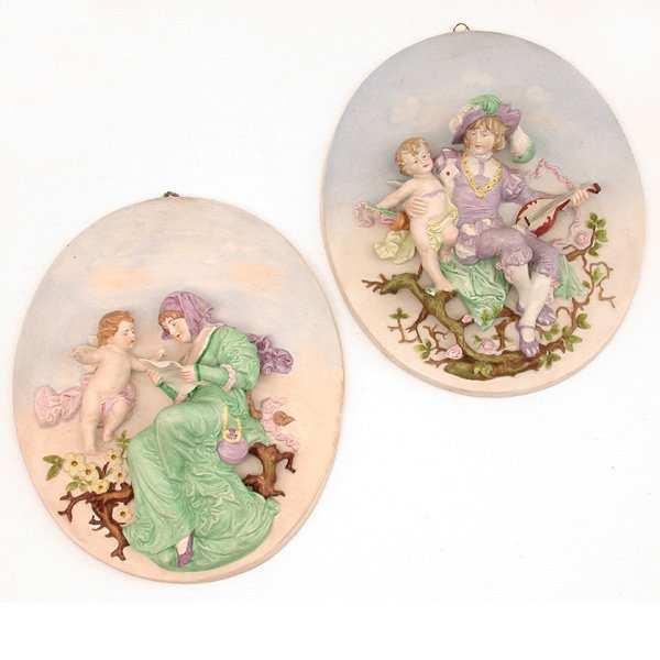Two German Bisque Figural Plaques: BISQUE PLAQUES. Two German bisque oval plaques decorated with scenes of modeled classical figures and putti, marked with blue crossed 'S' and 'Germany' to reverse, 10"h x 8"w, both in overall good con