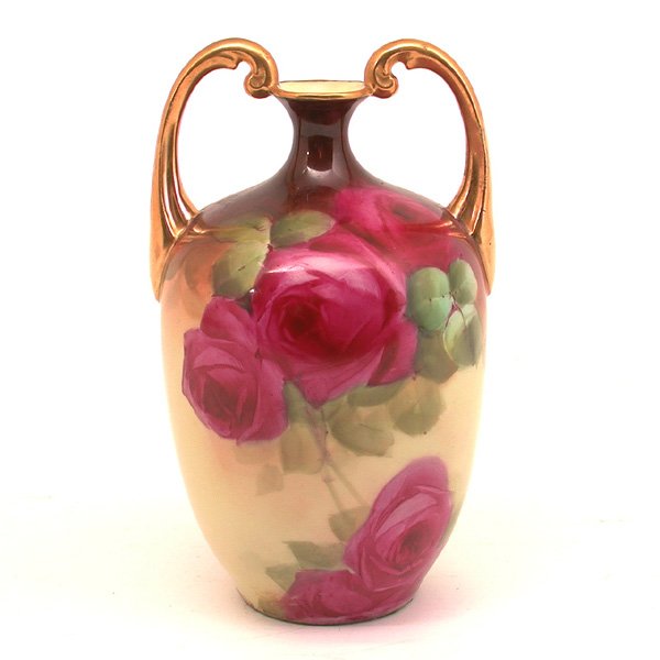 Limoges French Porcelain Bud Vase: VASE. French porcelain bud vase by Limoges, with gilt rim and scrolling double handles, the bulbous, amphora form body hand decorated with richly colored roses, stamped with Limoges mark and lion's he
