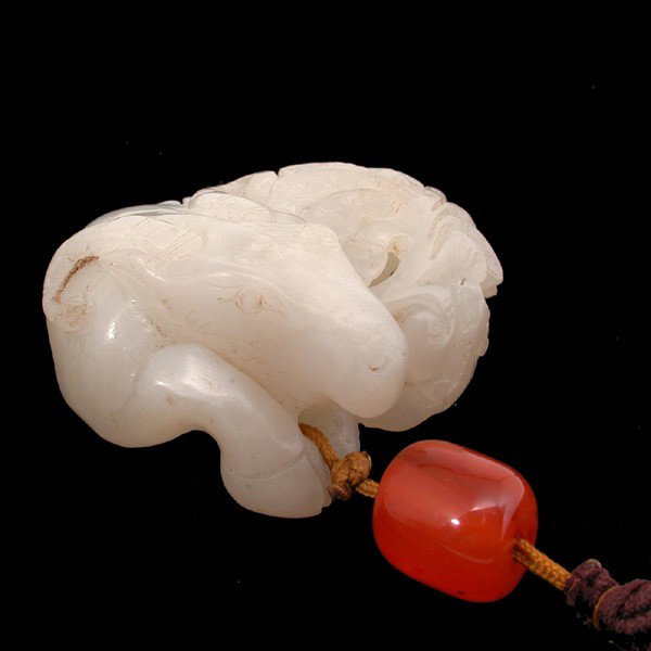 Chinese He Tian White Jade Ram Toggle: TOGGLE. Chinese he tian white jade toggle, carved after a coiled ram with a pierced leaf frond, approx. 2"d. In good condition, some very minor wear.