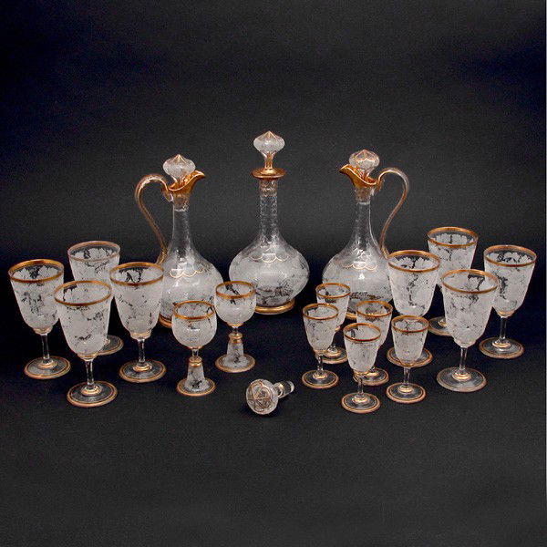 Etched Crystal Wine Set, Grape Design, 18 pieces: CRYSTAL. Etched Crystal and Gilt Rim Wine Set, consisting of 2 ewers,1 decanter, 8 wine, 5 port and 2 aperitif, all with a grape and leaf etched design, M monogram, a few minor flakes on bases, decant