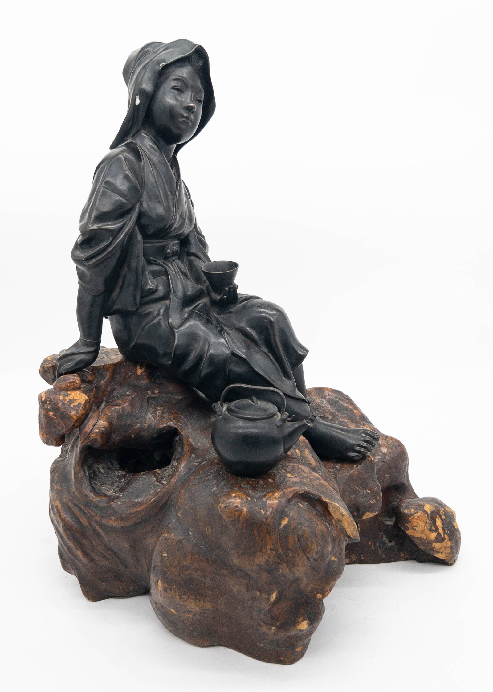 Japanese Bronze Maiden On Carved Wood Base: Japanese Bronze Maiden On Carved Wood Base. Meiji era (1868-1912). Large bronze okimono of a young woman on pilgrimage resting on a wood formed "rock", holding a cup in her hand. Teapot sits inserted 