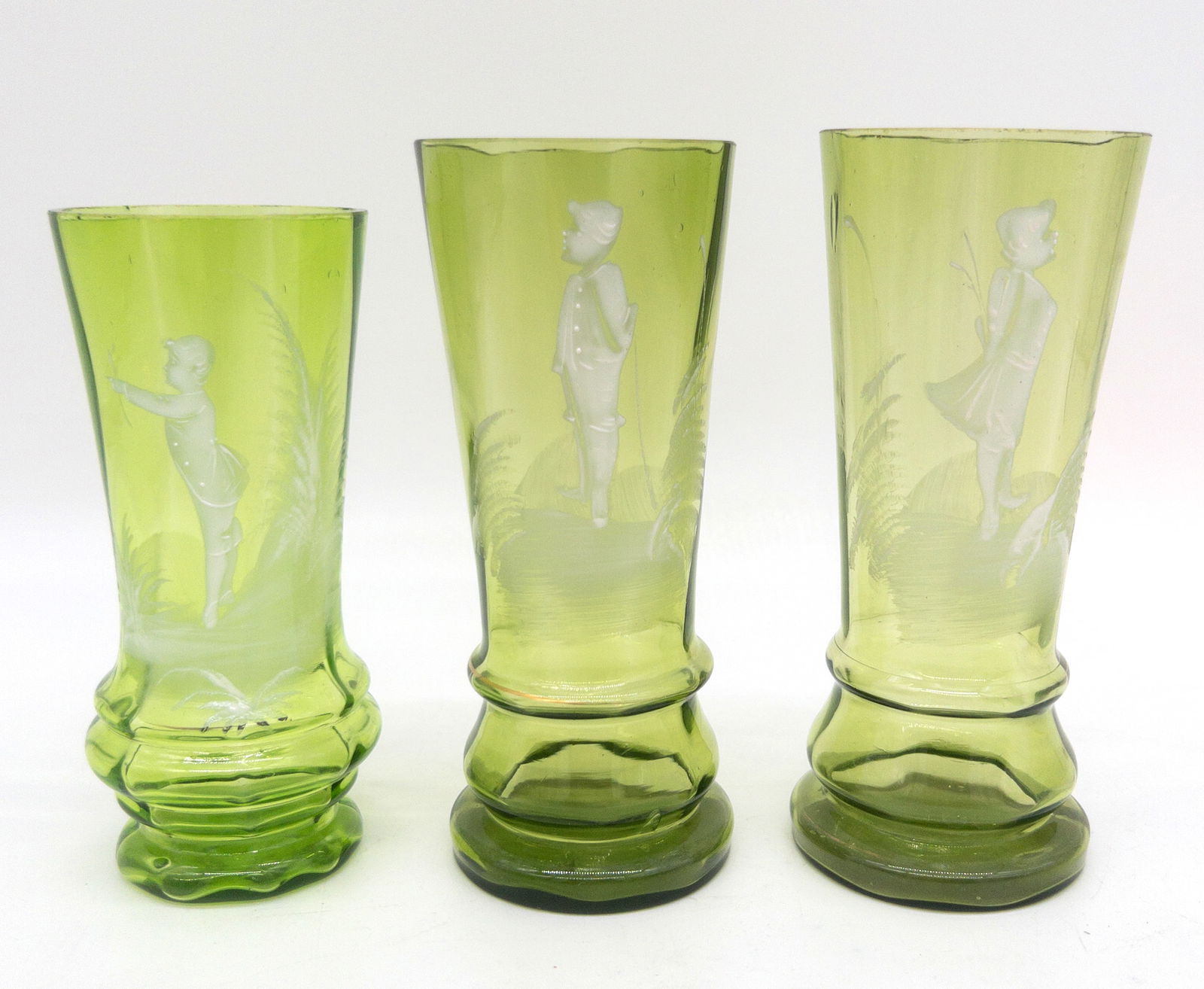 Three Mary Gregory Green Enamel Painted Glasses: Three Mary Gregory Green Enamel Painted Glasses. Measure appx 6" tall. Slight wear to enamel and gold decoration. Very minor chipping to rim of woman (slightly rough).