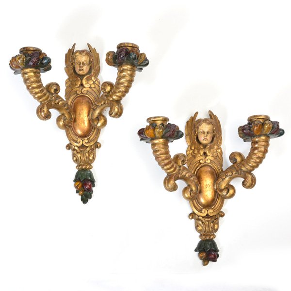 Pair of Continental Cupid Wall Sconces: Pair of Continental wooden wall sconces with gilded cupid heads and two arm painted cornucopia candle mounts, 17" h x 13 1/2" w x 7" d, good condition, loss to leaves at bottom on one sconce.