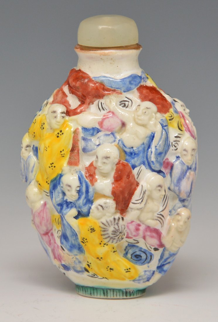 Porcelain Snuff Bottle. Circa: 1796-1820: Porcelain Snuff Bottle. A molded porcelain bottle with the 18 Lohan Buddhist Lore, standing on clouds. Chia Ching period with marks on base. Under-glaze of white, yellow, rose, red, green and blue on 
