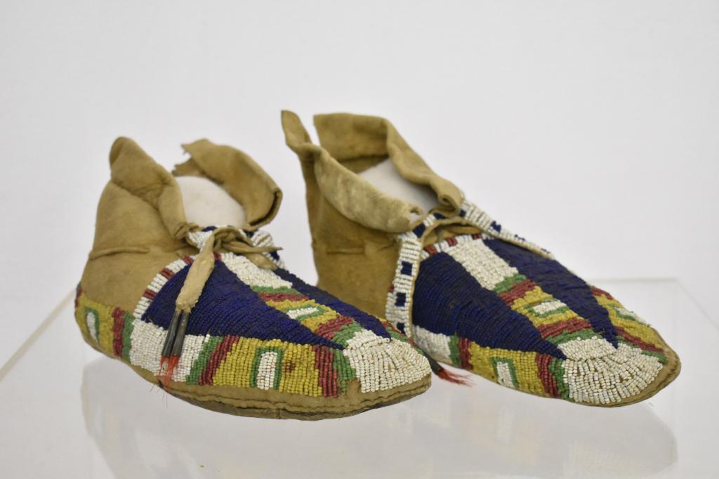 Meskwaki Native American Beaded Moccasins: Early 1900's, beleived to be Meskwaki female moccasins. Red, Yellow, blue, green and white beads with time tubes holding tassels. Measures 9". Condition very good. Dr. Michael O'Banion Estate.