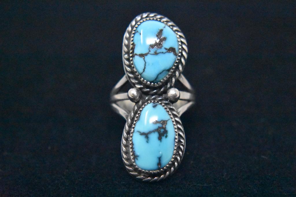 Turquoise 2 Stone Ring. Signed: 2 stones with rope around stones. Ring has markers mark that looks like either a bear or moose. See photos. Approximate size 11. Appears to be sterling.