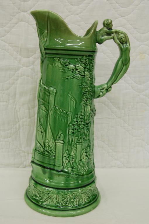 c. 1900 WELLER C. B. UPJOHN TANKARD. NUDE HANDLES: SIGNED C. B. UPJOHN. MOTIF IS CASTLE WITH MEN ON HORSES. GLOSS GLAZE. HANDLE IS NUDE MOTHER AND CHILD. HARD TO FIND. 17 1/2 INCHES TALL. VERY GOO D CONDITION.