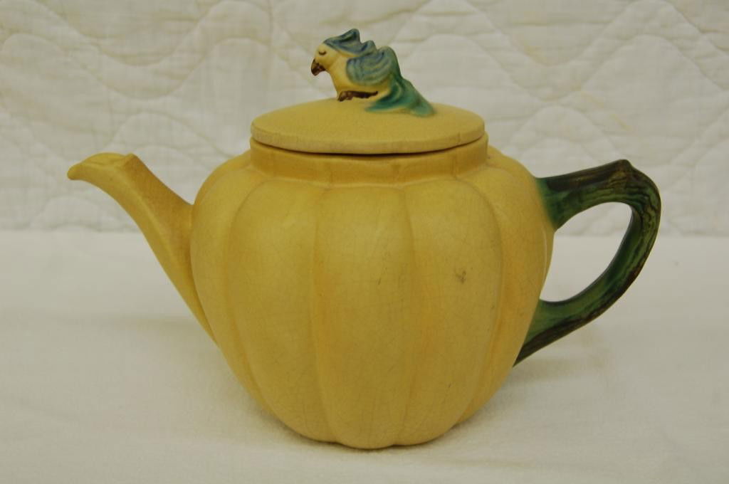 WELLER UTILITY WARE TEAPOT: TEAPOT IS RIBBED LIKE A PUMPKIN. LID HAS AN EXOTIC BIRD AS A FINIAL. ABOUT 7 INCHES TO TOP OF LID. C. 1928 HAND INCISED WELLER POTTERY. ALSO MARKED B OR D & E INTIALS OF ARTIST IN INK. CRAZED BUT IN G