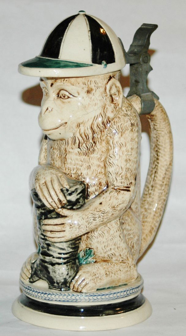 Jockey Monkey with Hat and Boot 1/2L Stein: Character Stein 1/2L Pottery. Monkey wears jockey cap and hugs a boot.