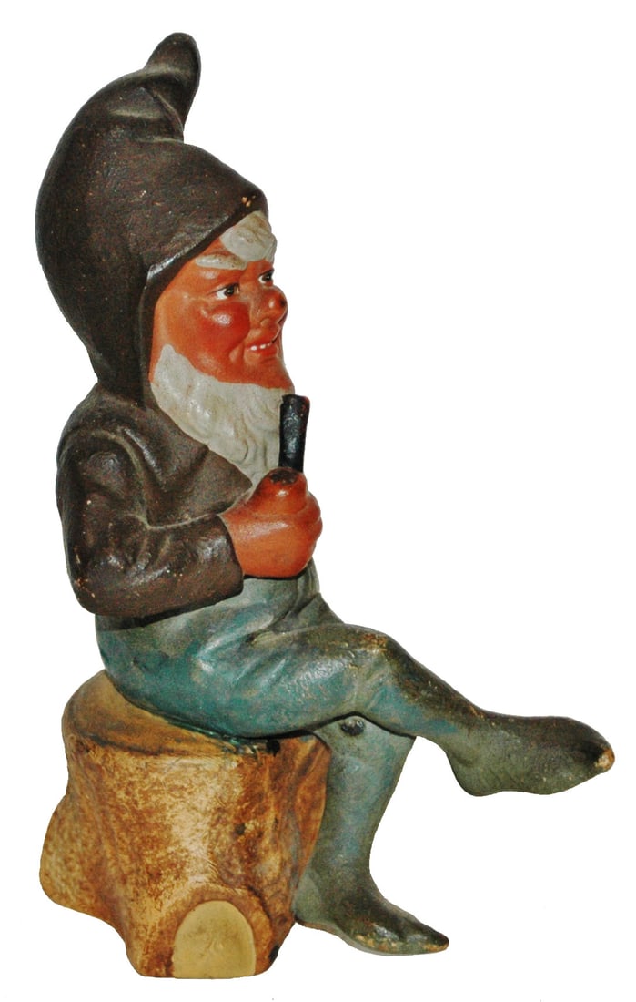 Terracotta Dwarf Smoking on a Stump figure: Terracotta 6 1/2” Figure. Dwarf sits on stump while smoking his pipe.