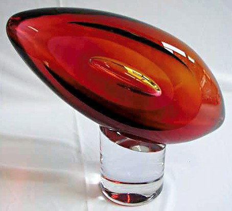 Swedish Crystal Studio Ahus Artglass Sculpture: Signed Studio Ahus art glass sculpture in the shape of a football upon a cylindrical base (the base is also glass and is attached) measuring approximately 11" height and 12" width.