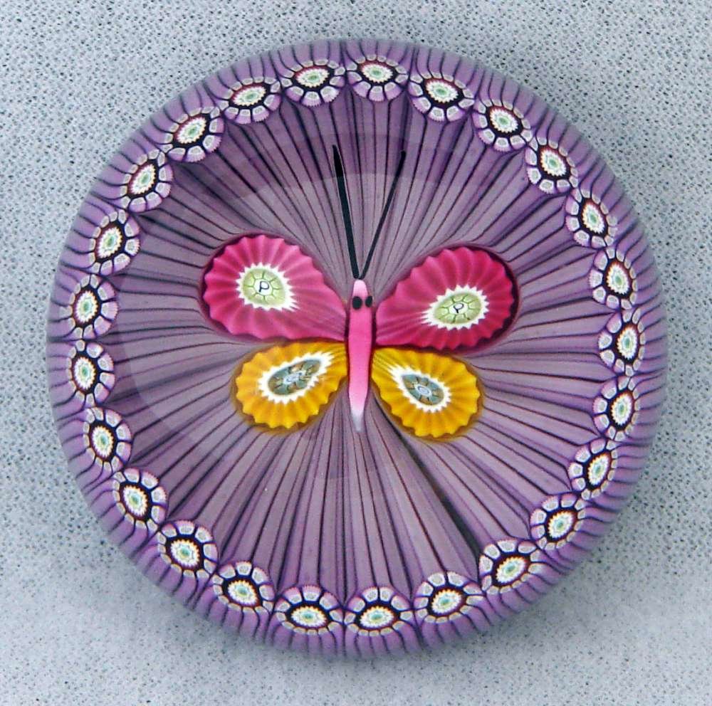 Perthshire Modern Paperweight c. 1988 Butterfly: Perthshire paperweight with a ""P"" signature cane and factory sticker on the bottom. 1988. Limited edition. Description: A miniature weight with a gold and rose butterfly. This floating butterfly is