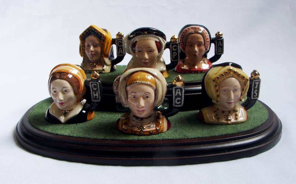 Royal Doulton Set 6 Tinies Henry VIII Wives: Set of six Royal Doulton tiny jugs depicting wives of Henry VIII, each approximately 1 3/4" height, on the original stand, including: Catherine of Aragon; Anne Boleyn; Ann of Cleves; Jane Seymour; Cat