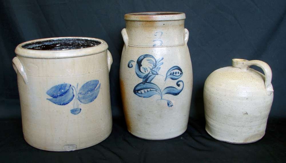 3 American Antique Stoneware Crocks + Whiskey: Three (3) American stoneware items including two crocks and one whiskey jug including a 14 ¾” 3 gallon crock with rosemahling ; 8 ½” unmarked stoneware whiskey jug and an 11” crock with impres