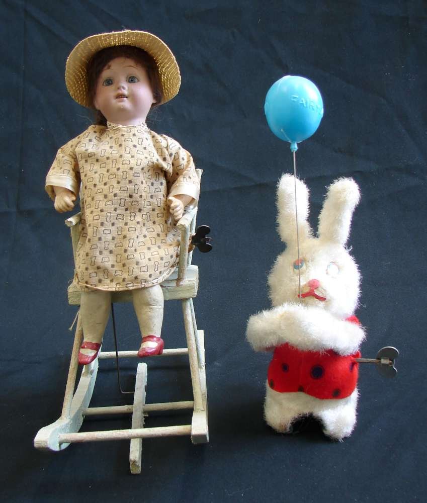 2 Circa 1900 Toys Wind Up Rocking Chair Doll Fairyland: Lot of two late 19th / early 20th century toys including: 1. a bisque head German doll on a rocking chair - this is a wind up toy in working condition, when it is wound up the chair rocks forward and 