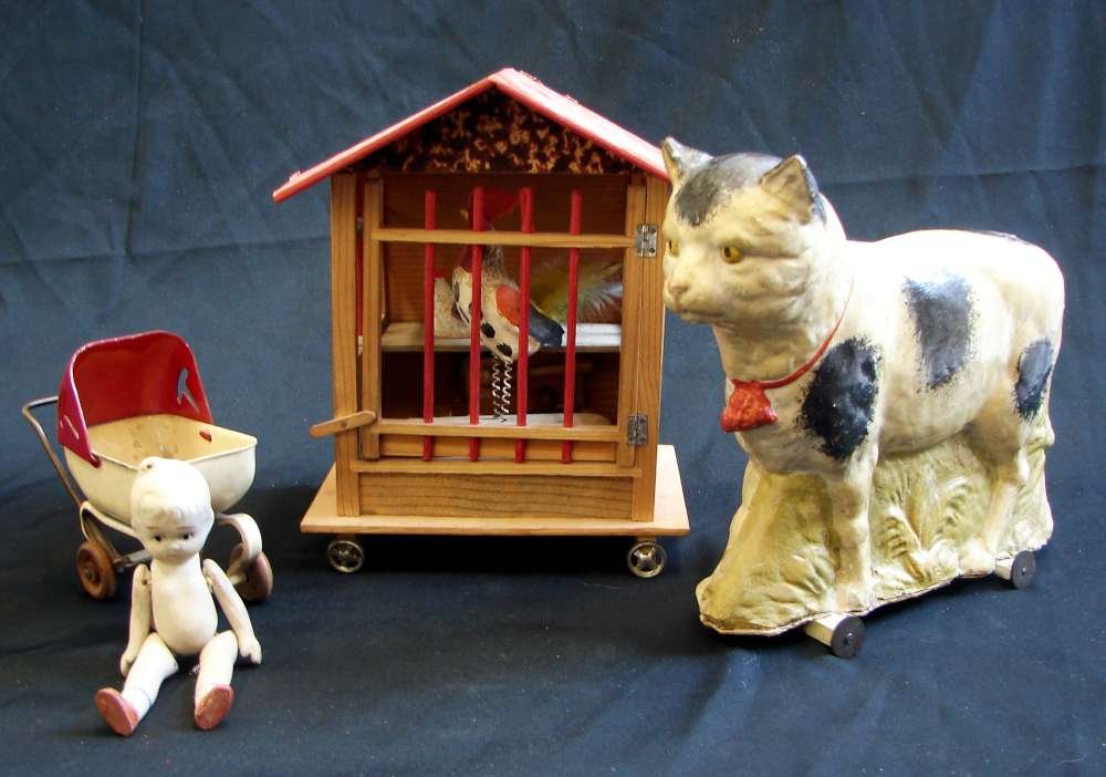 3 Circa 1900 Toys Paper Mache Cat Wheels Bisque Baby Do: Lot of 3 vintage toys including: 1. a circa 1910 German paper maché figure of a cat on wheels measuring 8" height; 2. an 8 1/2" wood toy of a chicken coop with two chickens on wheels; and 3. a bisque