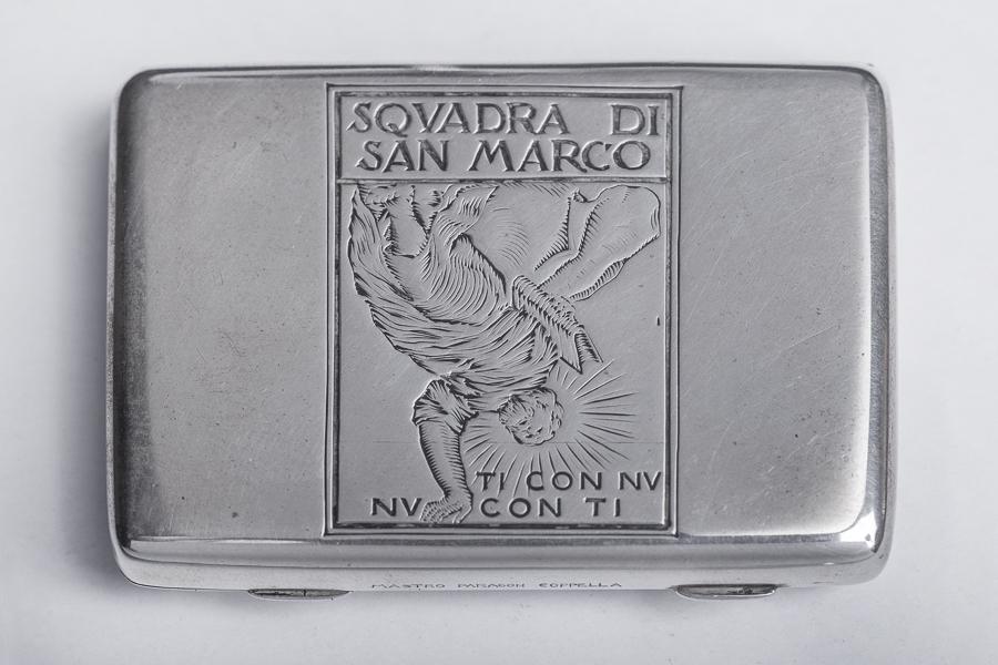 Tabacchiera in argento.: Mastro Paragon Coppella [pseud. di Mario Buccellati], Tabacchiera in argento. 1920 ca. Argento sbalzato e cesellato. cm 5x7. Inciso sul coperchio San Marco e il motto "ti con nu, nu con ti&q