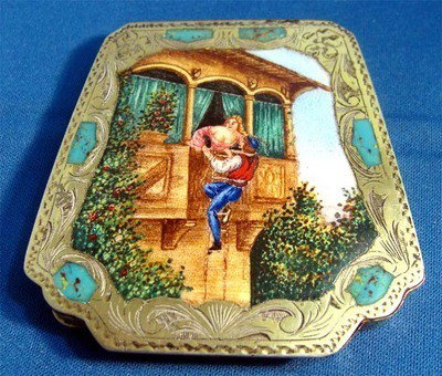Enamel Of Man Climbing Balcony & Girl Silver Compact: Rectangular silver compact with a large enamel painting of a man climbing a balcony to see his lover (romeo & juliet?). The painting is framed by nice engraved silver and turquoise enamel accents. Ins