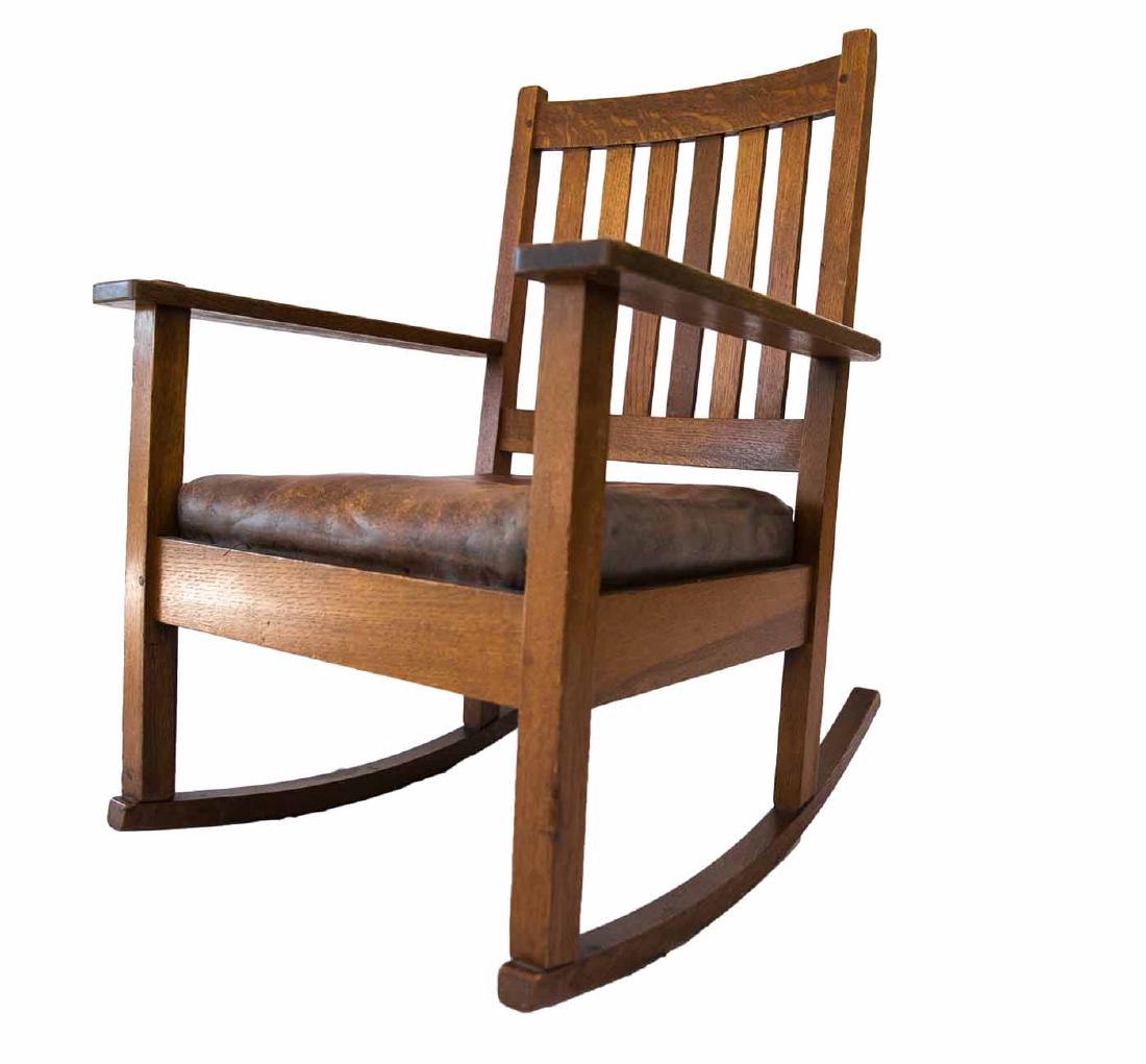 Gustav Stickley Oak Rocking Chair: (1) 35" h x 25 1/2" w. Oak with original patina. Original label underneath. NOTE - buyer is responsible all packing and shipping/transporting or local pickup.