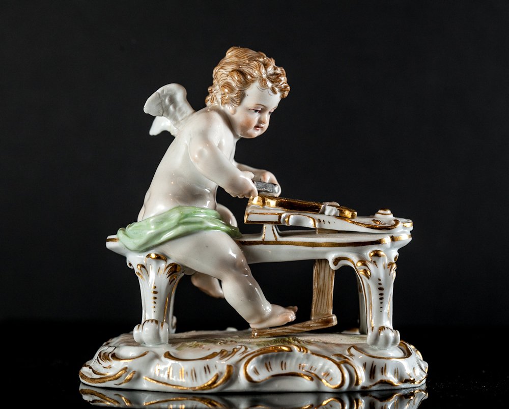Meissen Figurine: (1) 4 1/2"h x 4 1/2"w. Subject: Cherubim playing harpsichord. Marked on base with crossed swords. Minor damage to instrument