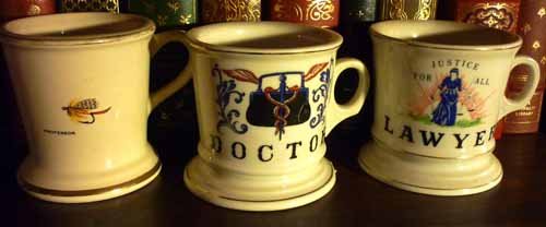 Antique Occupational Shaving Mugs: Including: (1) Atlas China Professor shaving mug with fishing lure, (1) marked: Doctor with medical bag, (1) marked: Lawyer Justice for All. Condition on all Good. All 4"h.