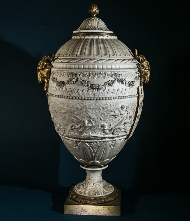 Sevres Bisque Urn: (1) Early 20th Century, Sevres Bisque Urn. 21 1/4" high x 11 1/2" wide x 31 1/2" in dia. Bacchus scene floral bunting with bronze ormolu rams head handles. Seves incised mark with a paper label that s