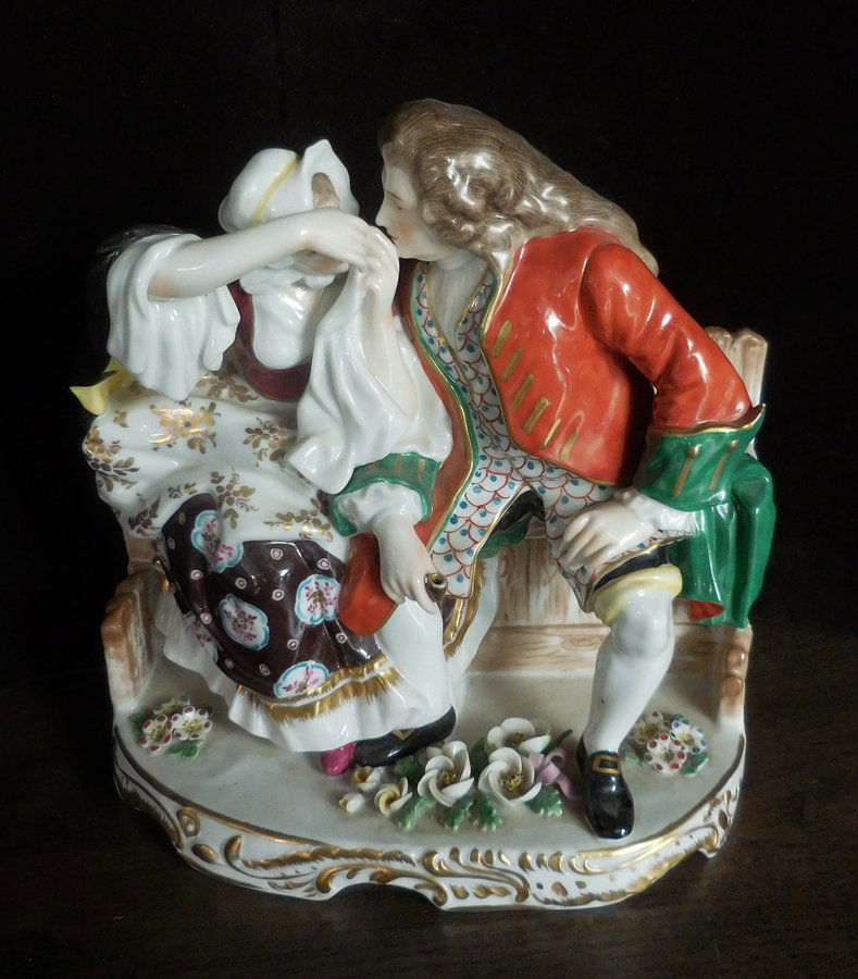 19th Century Porcelain Figural Group: (1) 8 1/2"h x 8"w. White porcelain with hand painted decoration. Subject: man and woman sitting on a wood bench.
